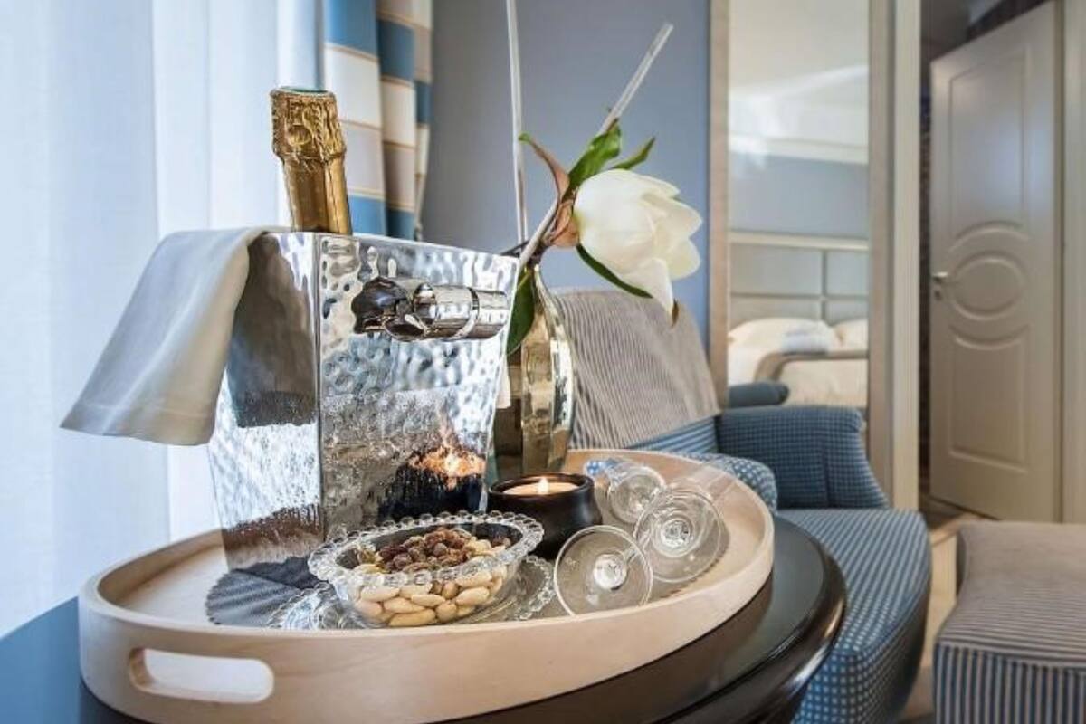 A tray with a bottle of champagne, a candle, and a flower on a table in a room with a blue sofa and a door in the background.