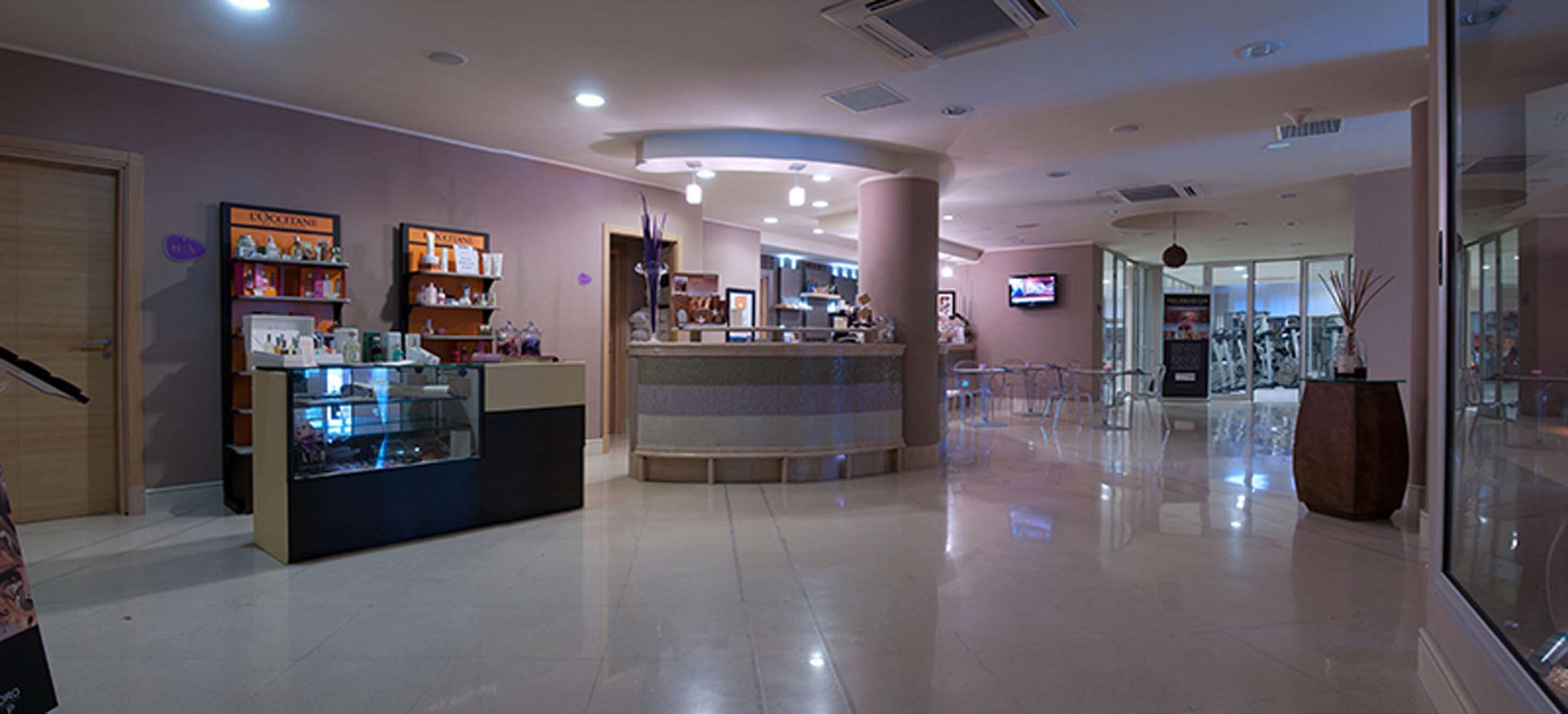 A modern interior with a reception desk, a counter with a glass display, and a TV mounted on the wall.