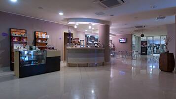 A modern interior with a reception desk, a counter with a glass display, and a TV mounted on the wall.