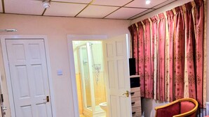 A hotel room with a bed, a chair, a door, and a bathroom visible through an open door. - The Albany Hotel (Blackpool)