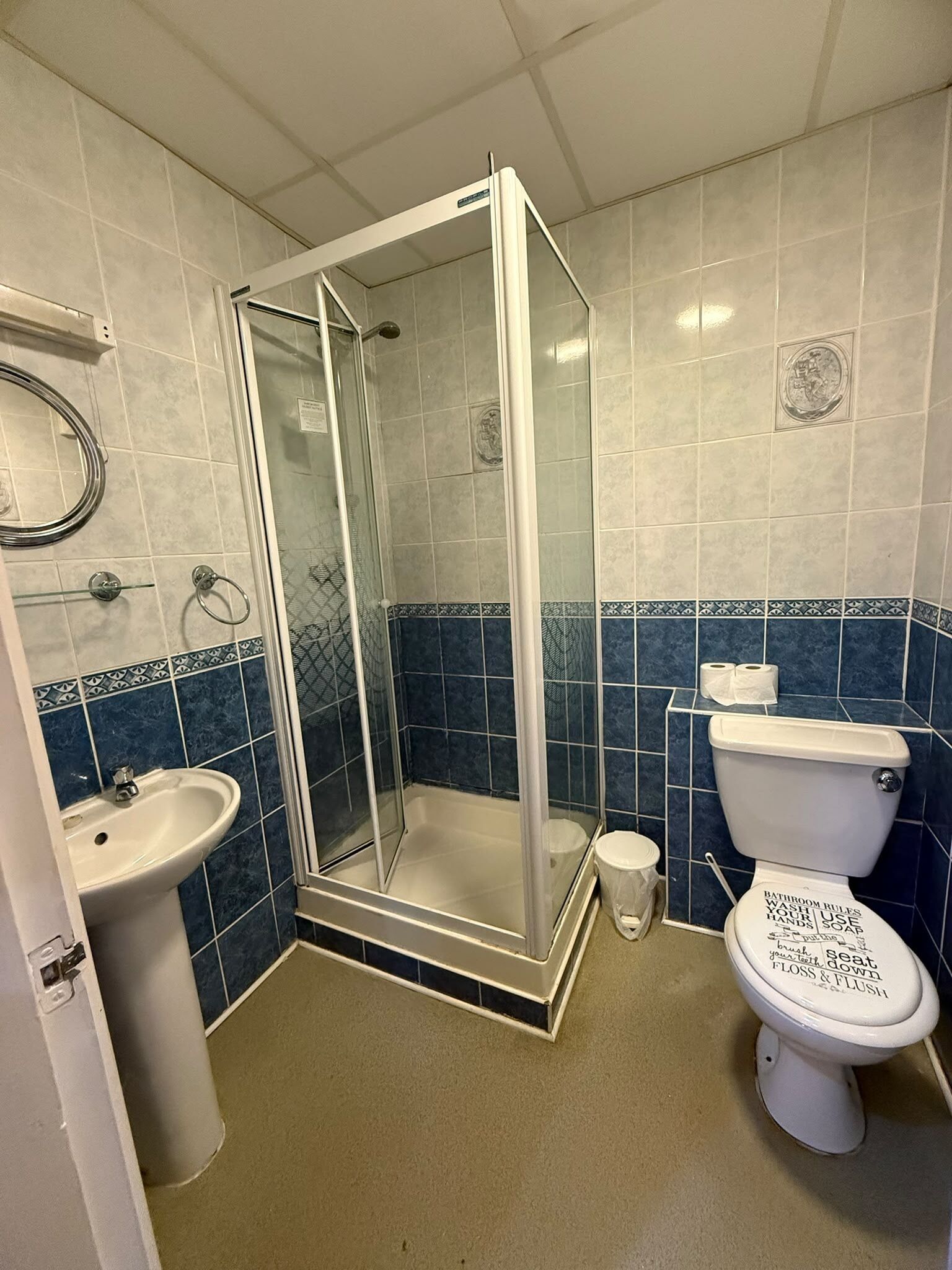 A bathroom with a glass-enclosed shower, a sink, and a toilet.