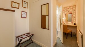 Un couloir avec un banc en bois, un miroir et des certificats encadrés accrochés au mur.