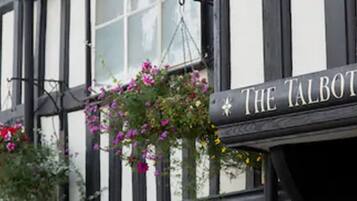 A building with black and white timber framing, a sign reading "The Talbot," and hanging flower baskets.