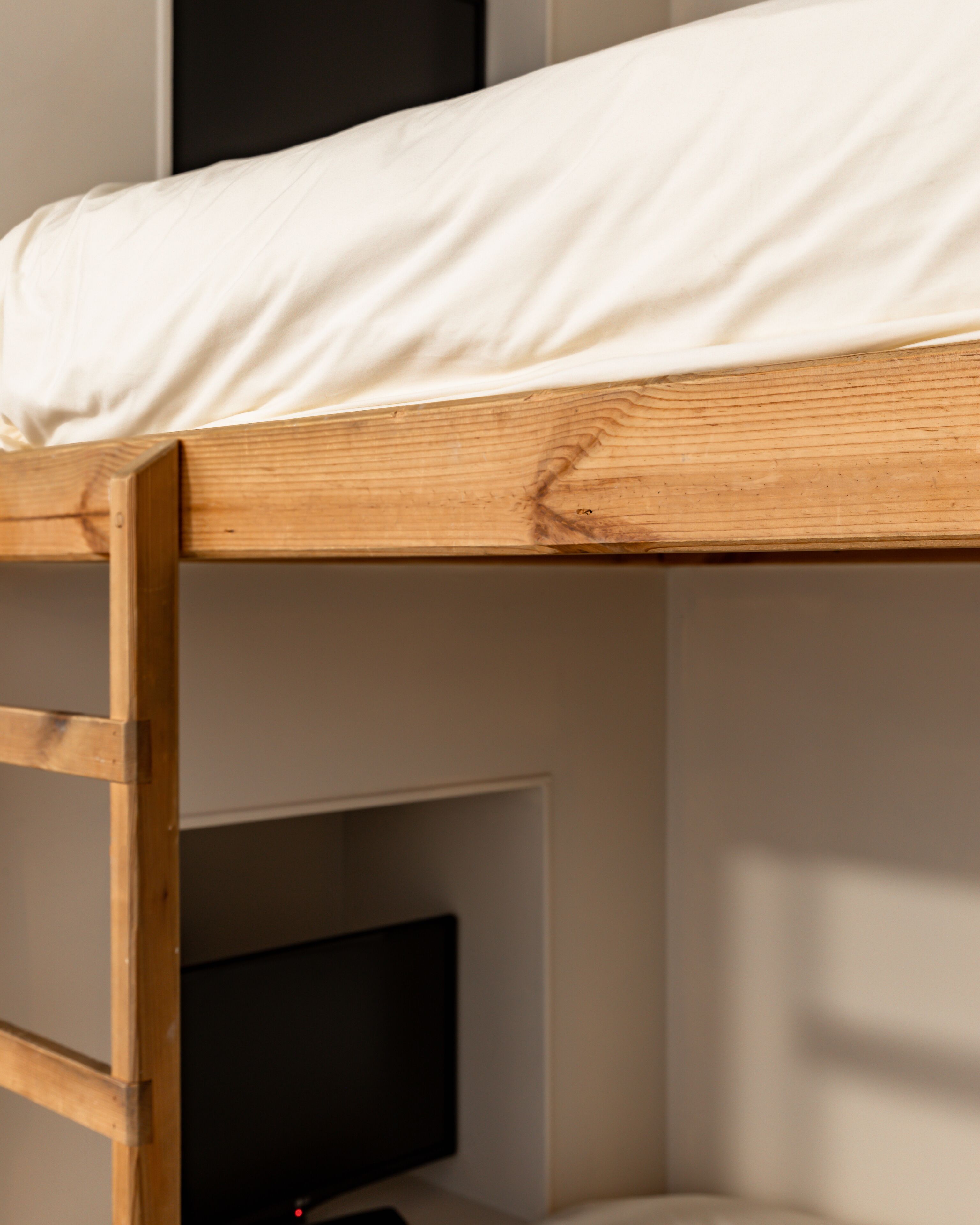 Una cama litera con estructura de madera y colchón blanco.