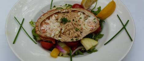 A plate of food with a salad and a stuffed item, garnished with lemon and chives.