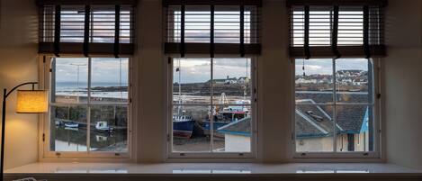 Quarto com três janelas com vista para um porto, uma lâmpada e um radiador.