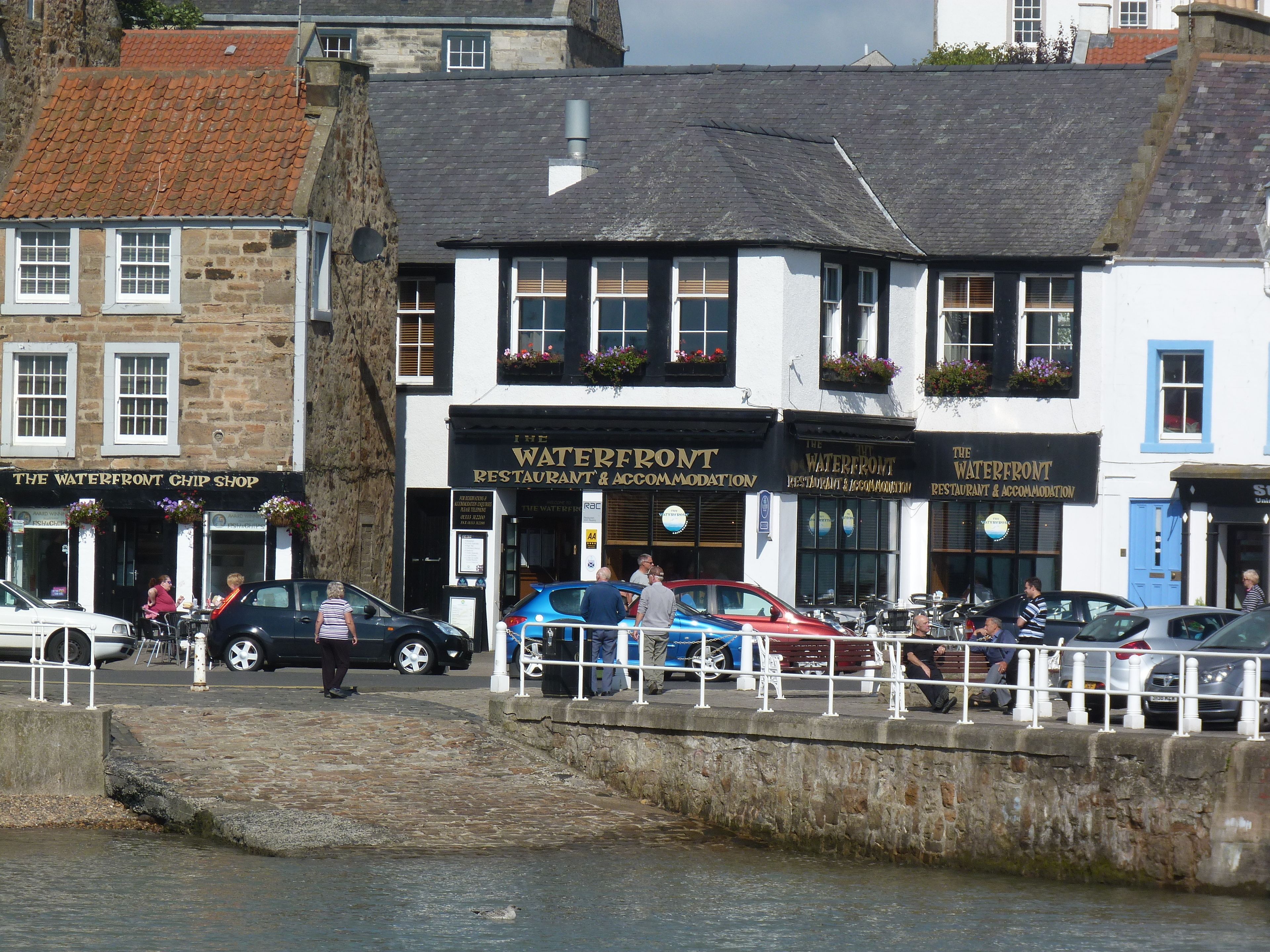 A waterfront building with multiple signs for 'The Waterfront Restaurant & Accommodation'.
