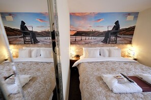 A hotel room with two beds, a large painting of a sunset scene, and a mirror reflecting the room. - Toulson Court (Scarborough)