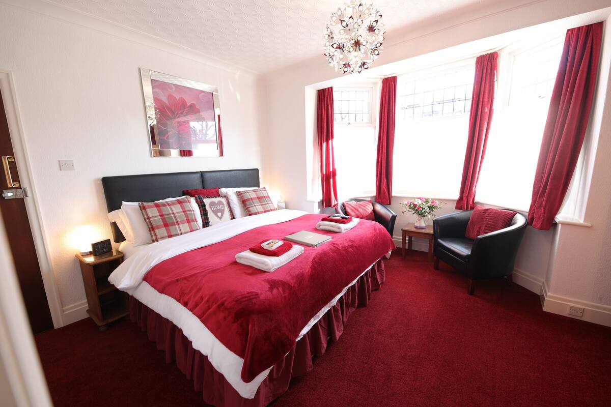 A spacious bedroom with a large bed, a desk, and a chair.
