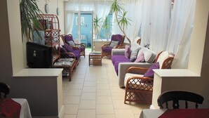 A sunlit living room with a glass ceiling, wicker furniture, and potted plants. - Toulson Court (Scarborough)