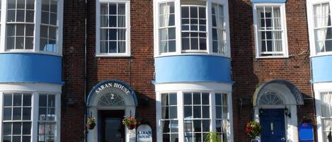 A row of brick buildings with blue window frames and a sign reading "AARAN HOUSE".