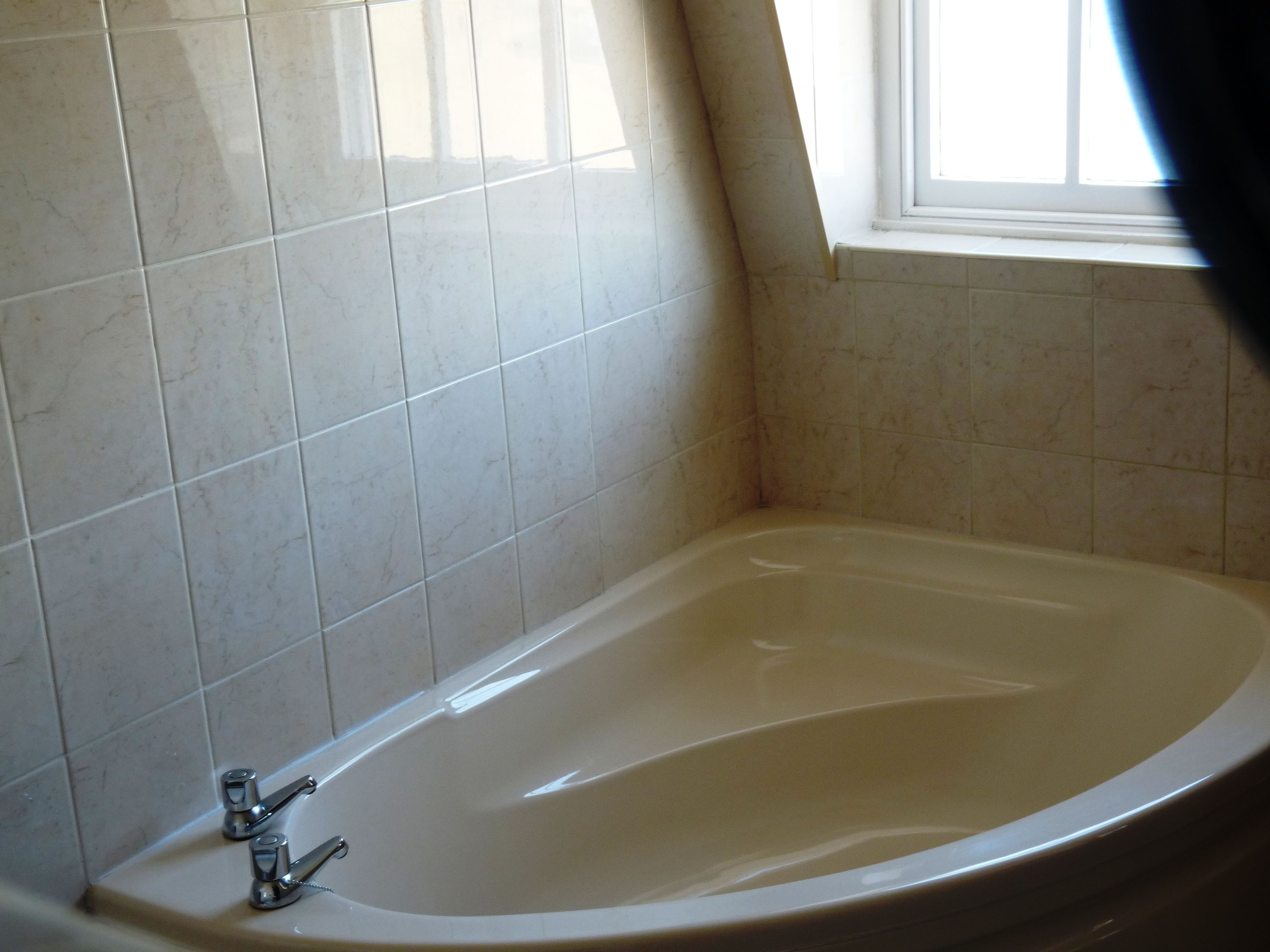 A bathroom with a bathtub, tiled walls, and a window.