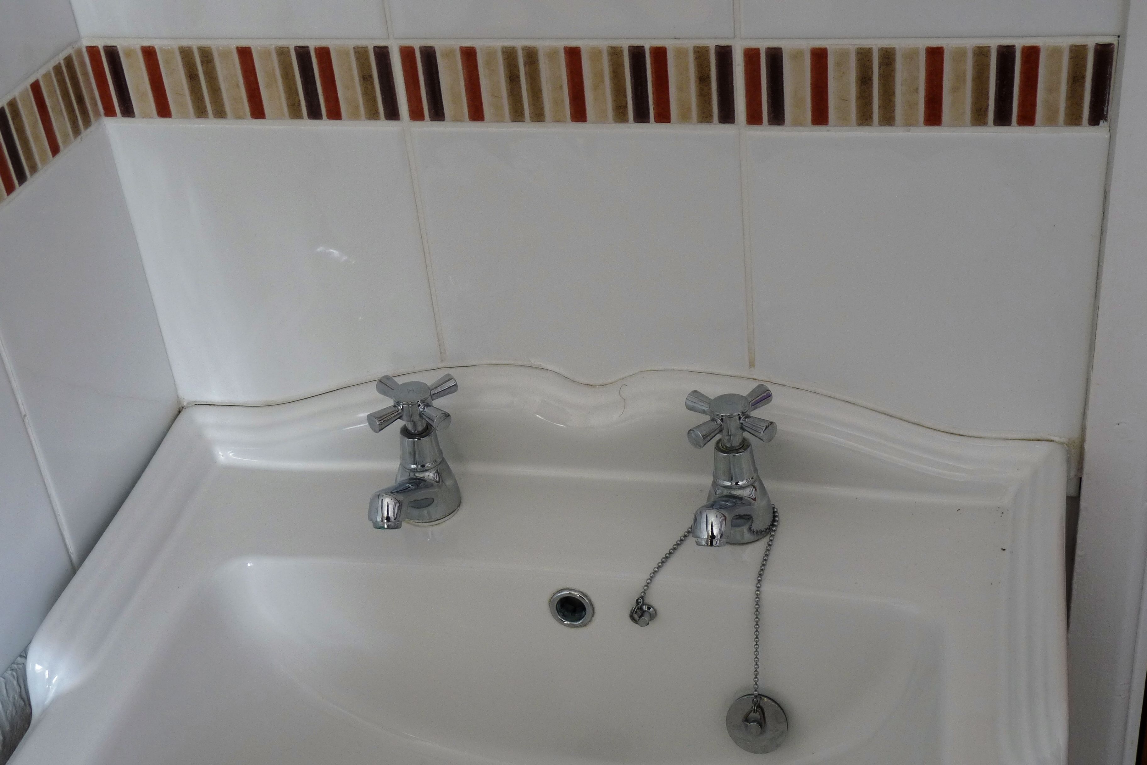 A white bathtub with two faucets and a drain.