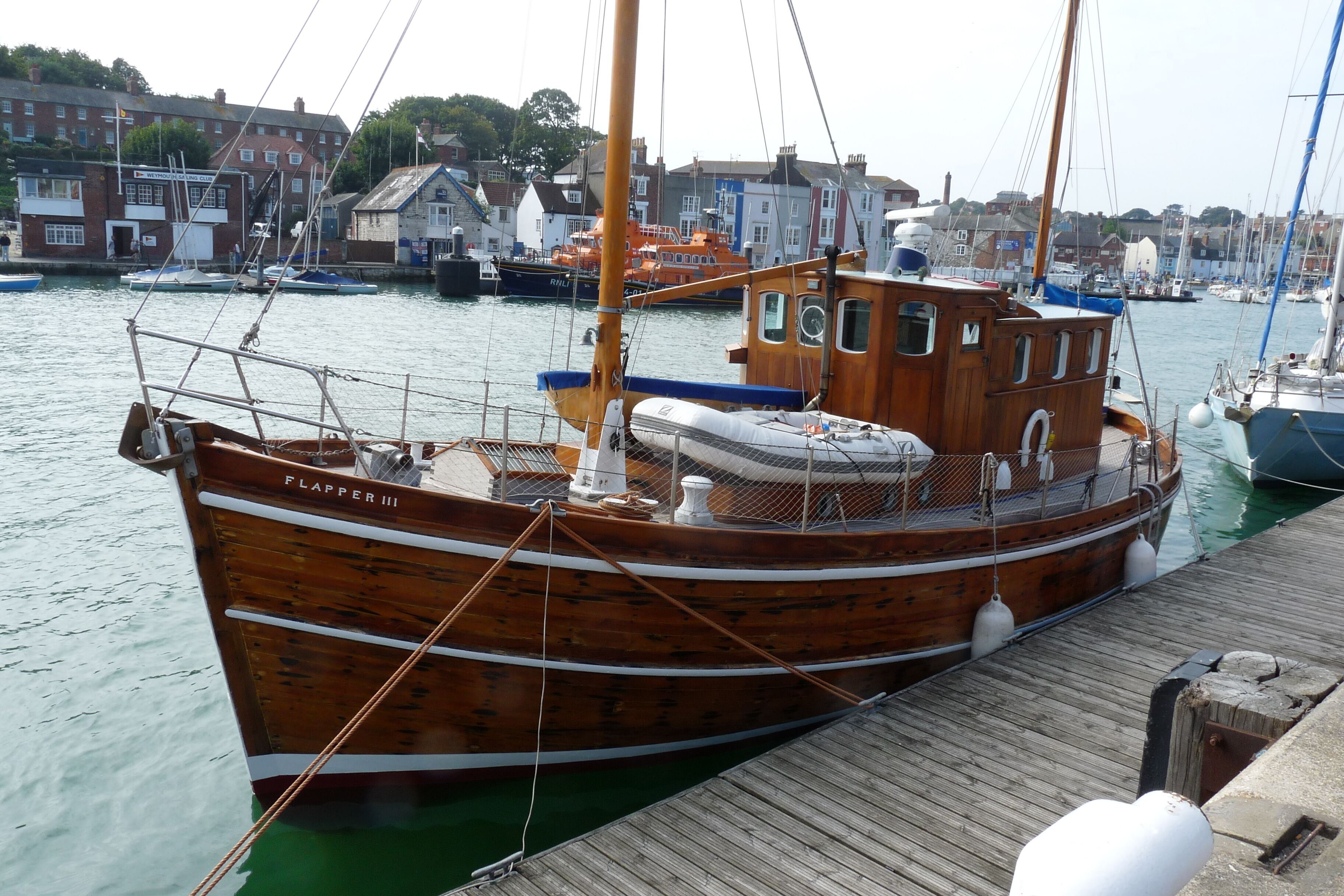 A wooden boat docked at a pier with a town in the background.