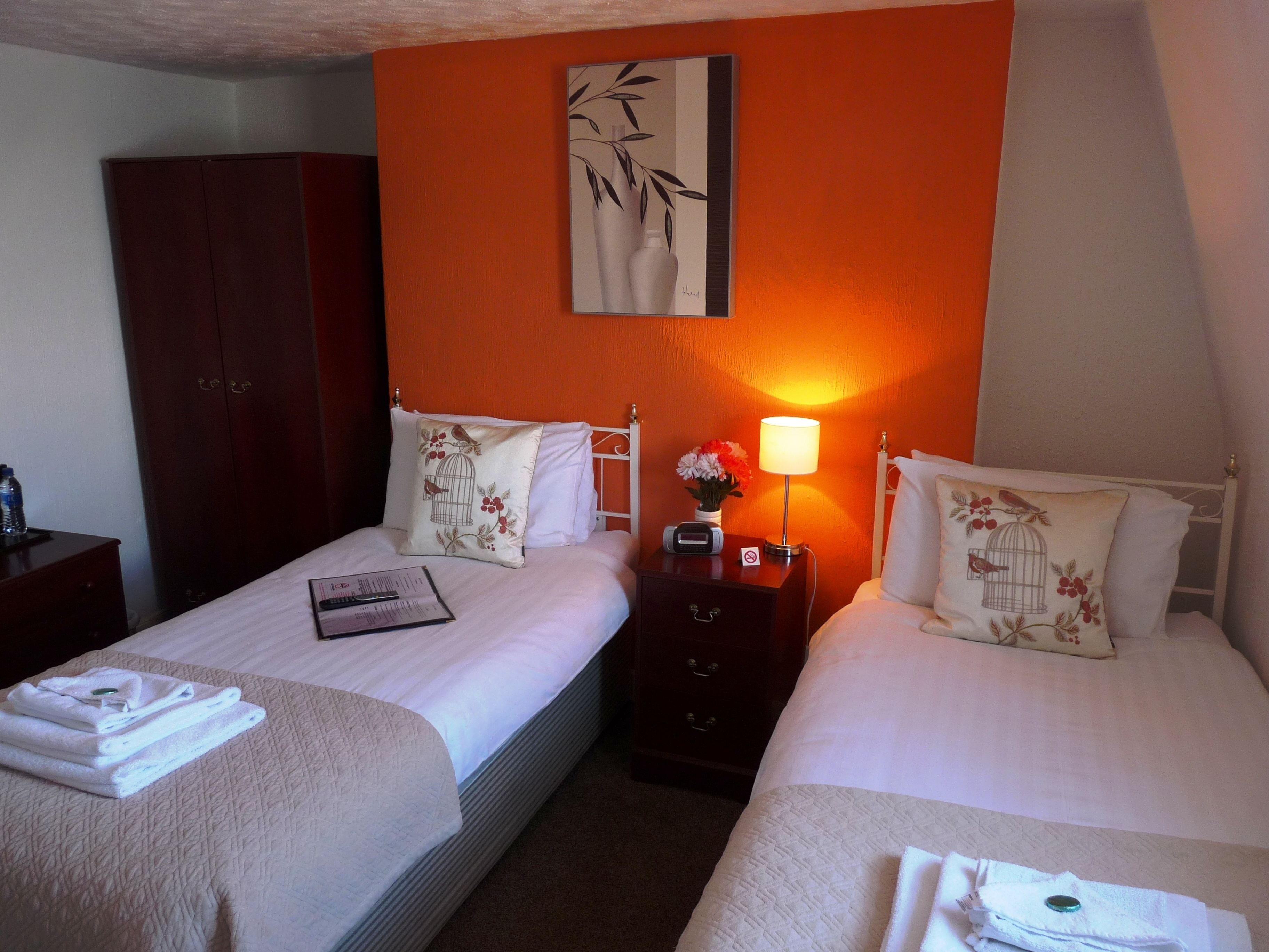Une chambre d’hôtel avec deux lits, une table de chevet avec une lampe, une armoire et un tableau au mur.