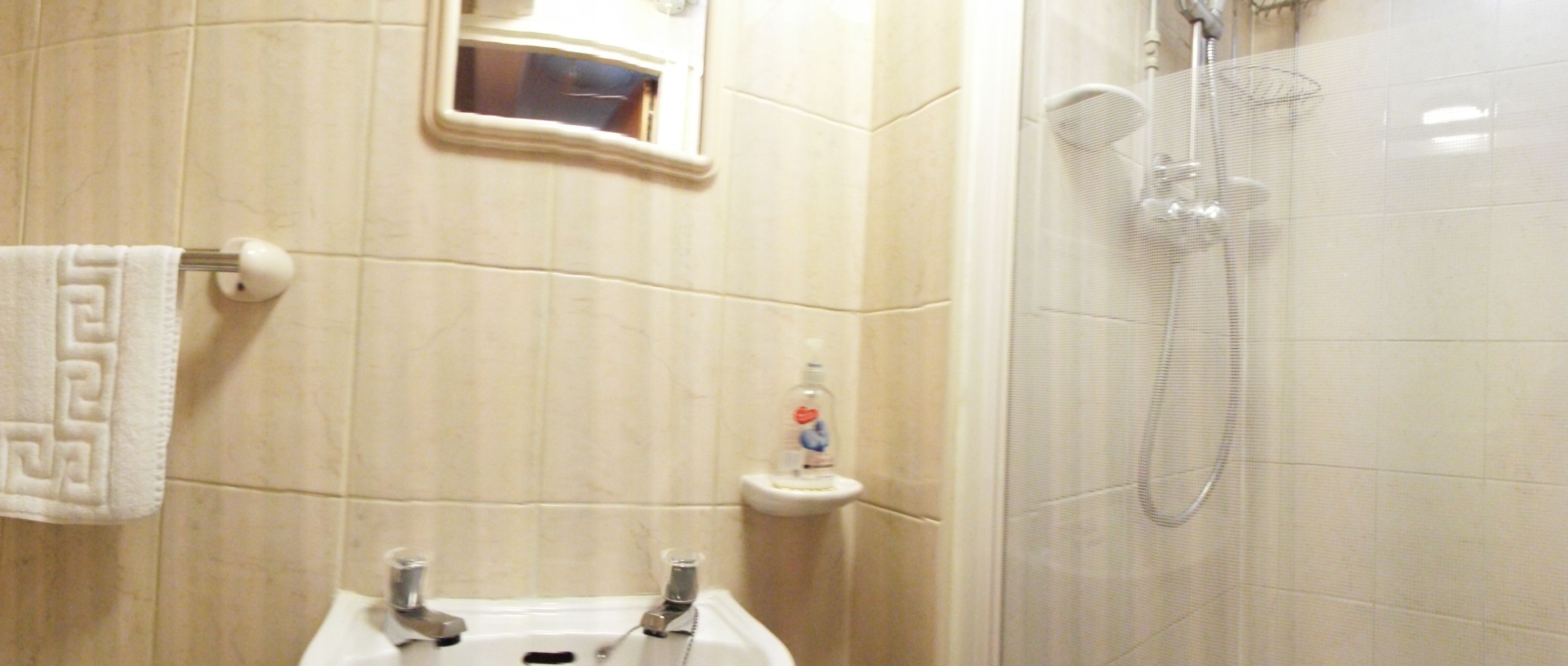 Un baño con lavabo, espejo, toallero y ducha.