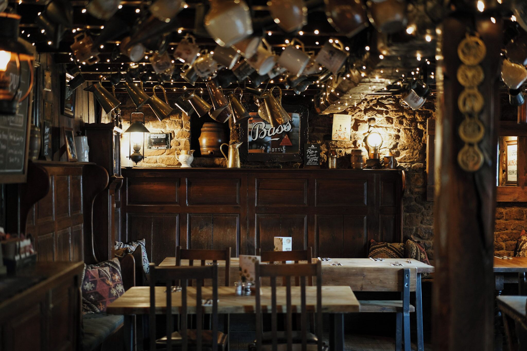 Un intérieur rustique avec des meubles en bois, un mur en pierre et des tasses suspendues.