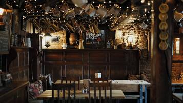 Un intérieur rustique avec des meubles en bois, un mur en pierre et des tasses suspendues.