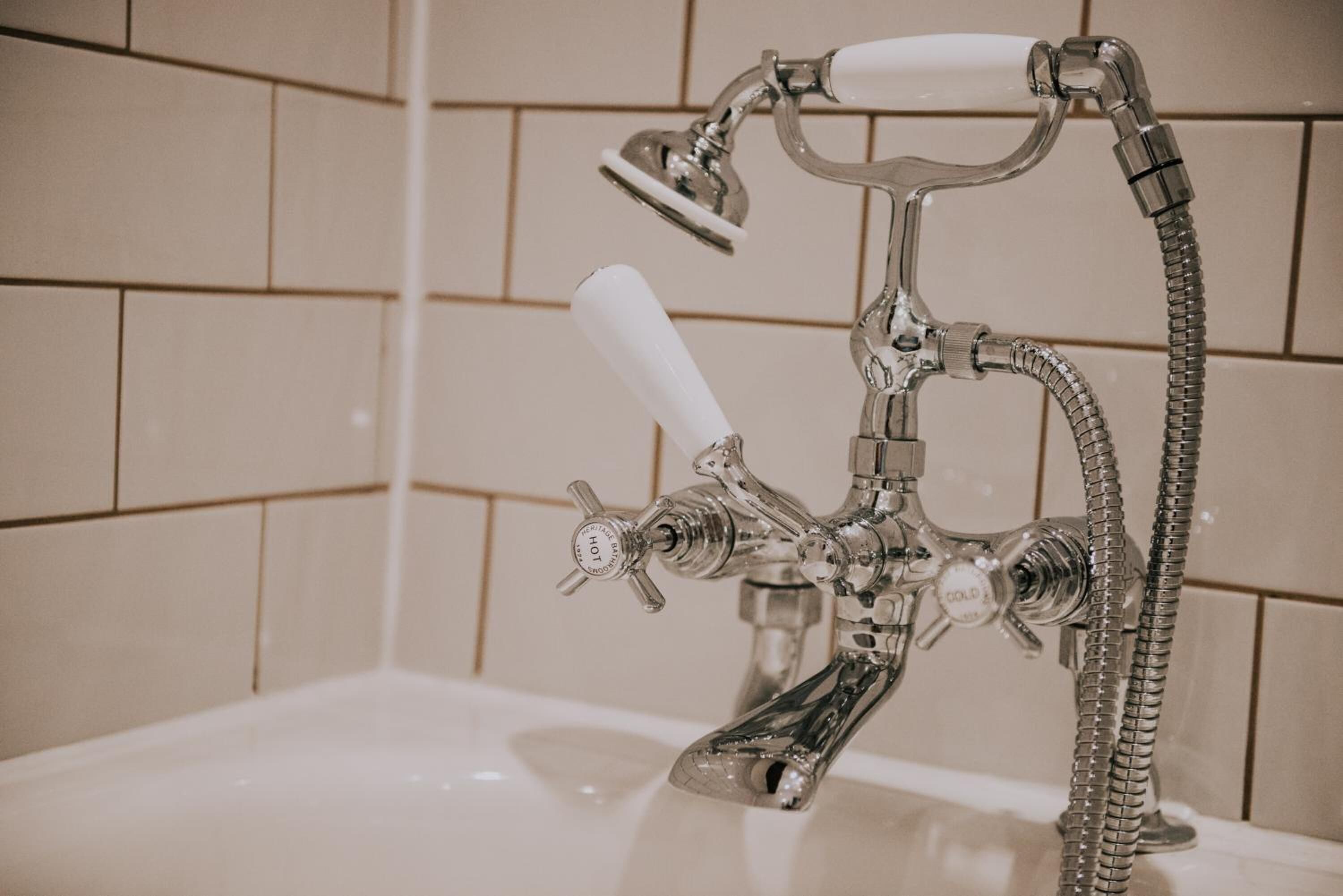Un baño con cabezal de ducha cromado, ducha de mano y grifo de mano.