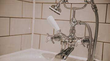 Un baño con cabezal de ducha cromado, ducha de mano y grifo de mano.