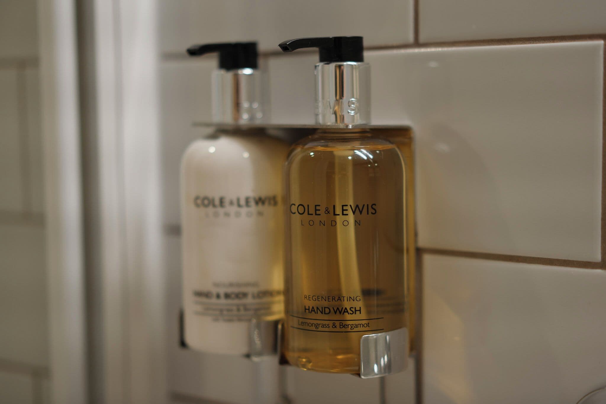 Two bottles of hand wash soap by Cole & Lewis London on a tiled wall.