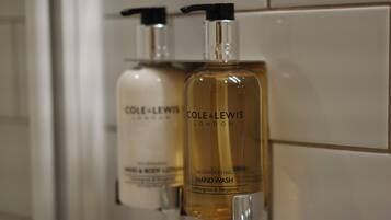 Two bottles of hand wash soap by Cole & Lewis London on a tiled wall.
