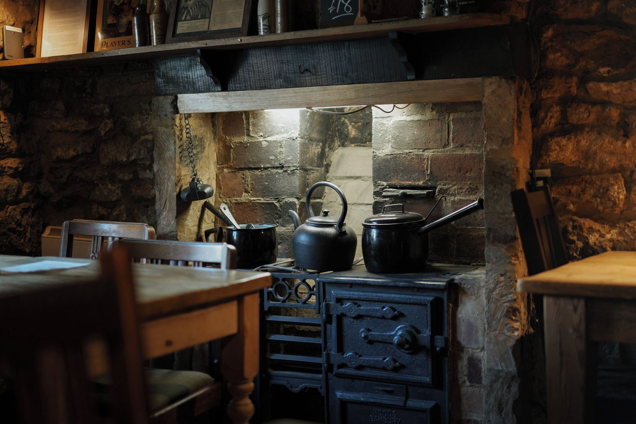 Une cuisine rustique avec un mur en pierre, des meubles en bois et un poêle d’époque.