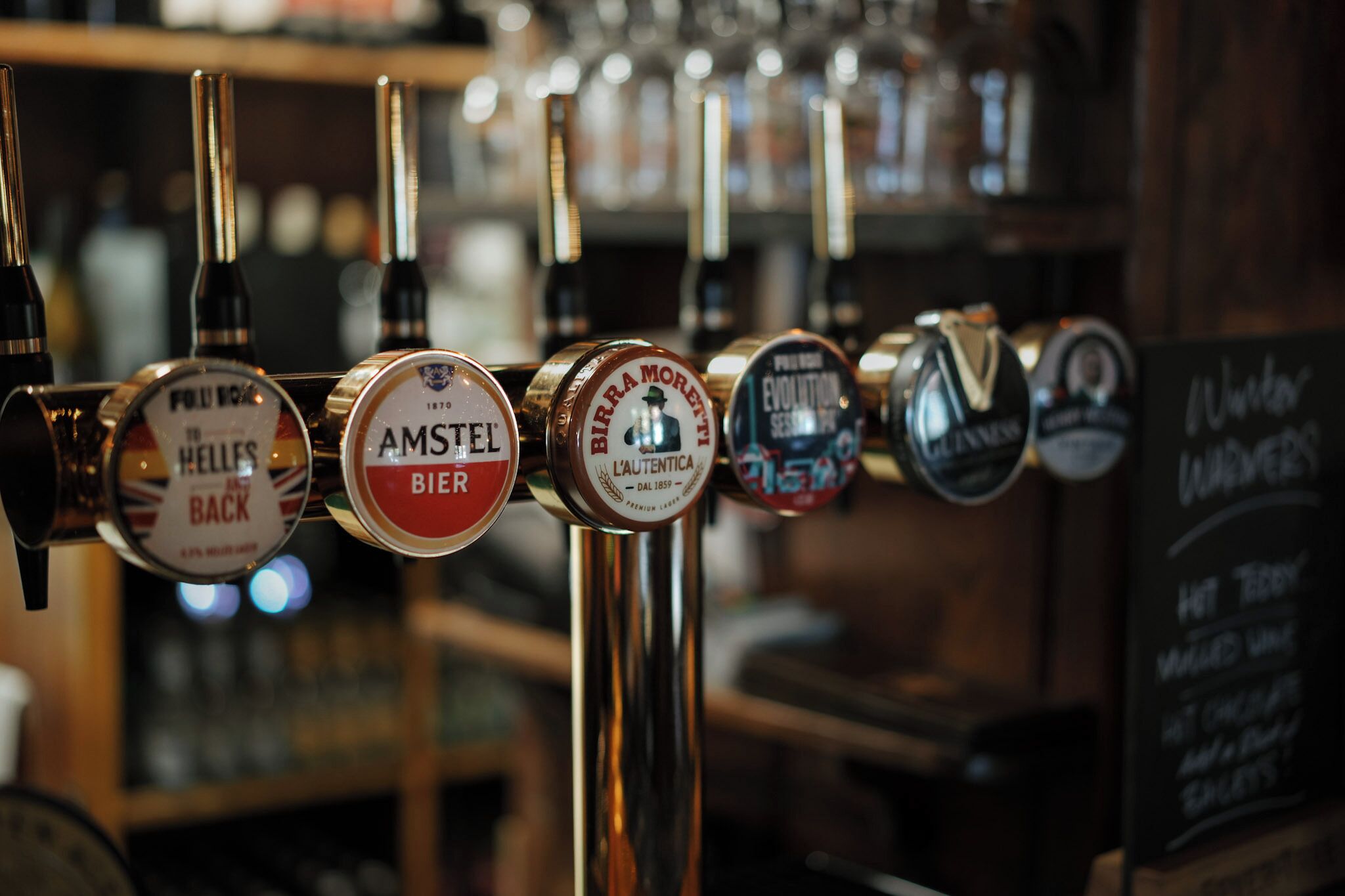 A row of beer taps with labels indicating different types of beer.