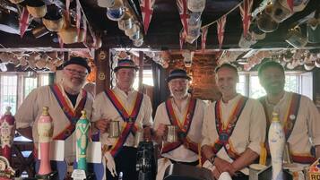 A group of men in ceremonial attire standing in a rustic setting with various beer taps and bottles.
