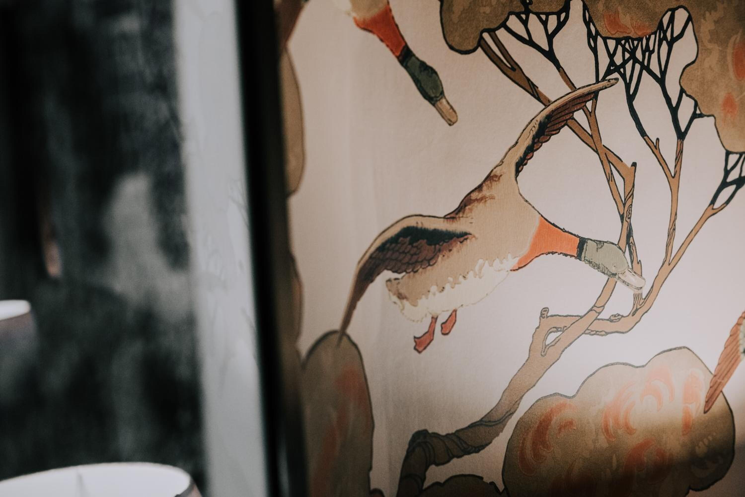 Un mur orné d’une fresque représentant un oiseau et des branches.