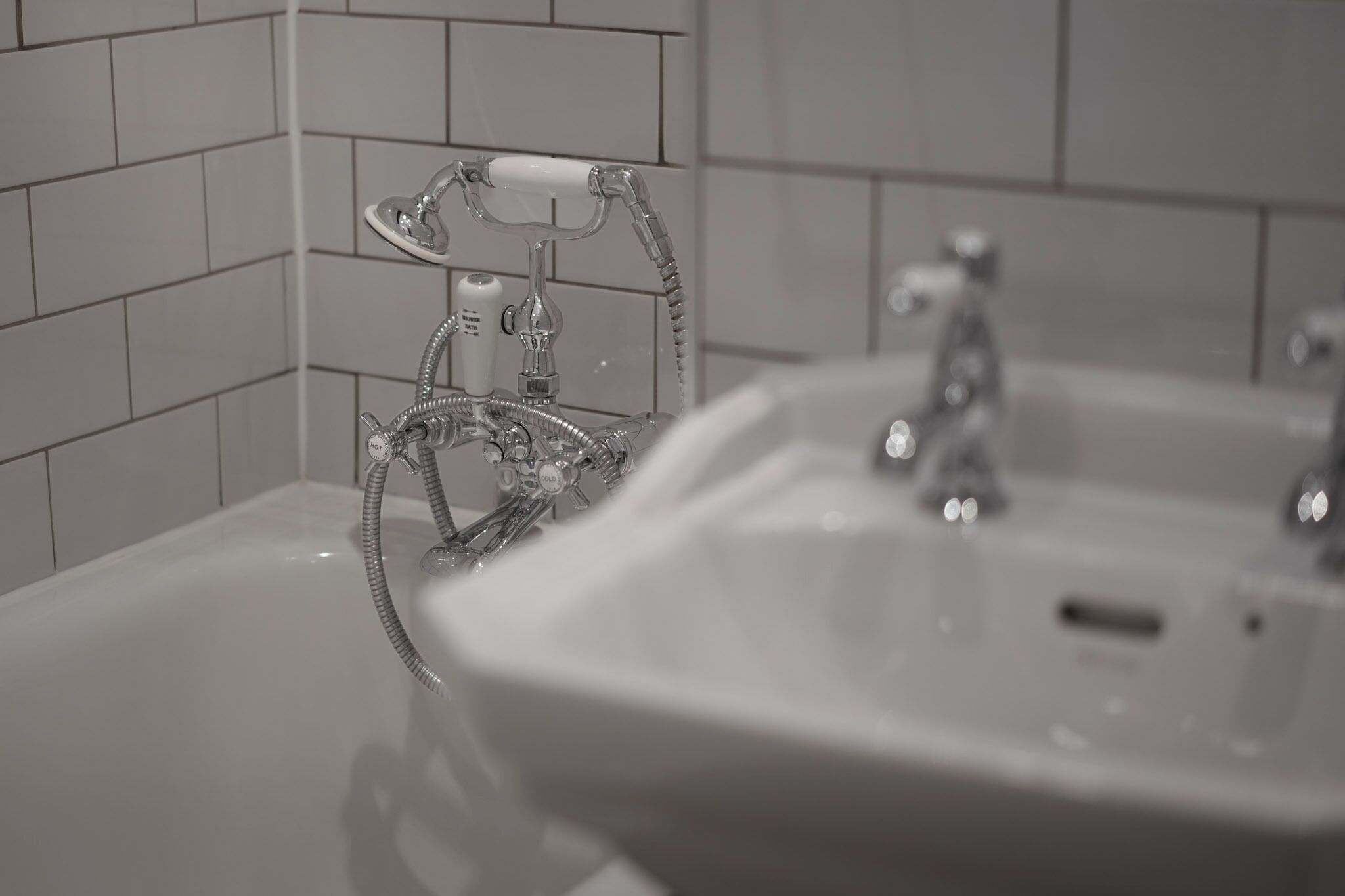 A bathroom with a bathtub, a shower with a flexible hose, and a sink.