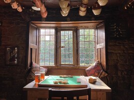 A cozy room with a wooden table, two windows, and a green felt board game.