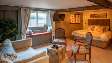 Een gezellige kamer met een bed, twee fauteuils, een bank en een raam met gordijnen.