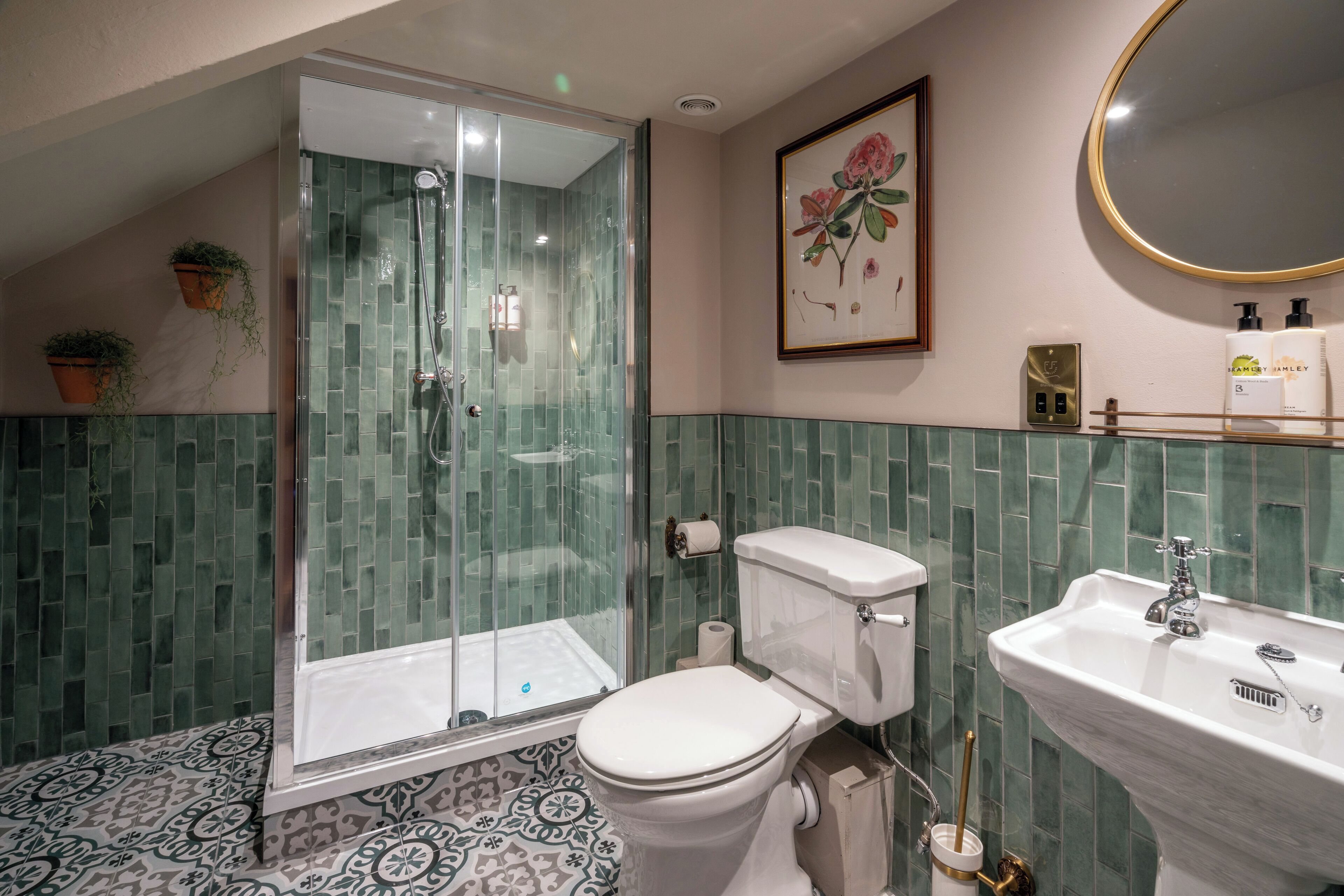 A bathroom with a glass-enclosed shower, a toilet, a sink, and a framed floral artwork on the wall.