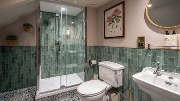 A bathroom with a glass-enclosed shower, a toilet, a sink, and a framed floral artwork on the wall.