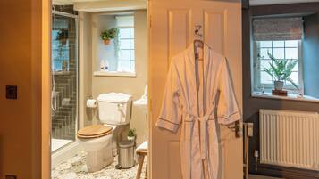 A bathroom with a shower, toilet, and a hanging bathrobe.