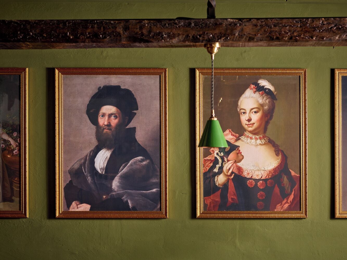 Tres retratos enmarcados sobre una pared de fondo verde.
