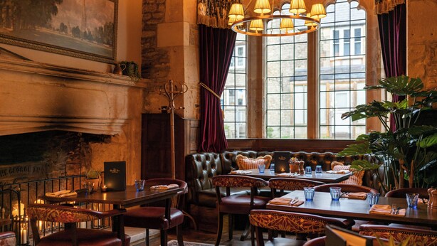 Un restaurant doté d’une cheminée, de sièges en cuir et de grandes fenêtres.