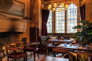 A restaurant with a fireplace, leather seating, and large windows. - The George Inn and The Plaine (Bath)