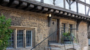Un bâtiment en pierre avec une porte en bois portant l’inscription « Salle d’entraînement », des marches en pierre et une rambarde en métal.