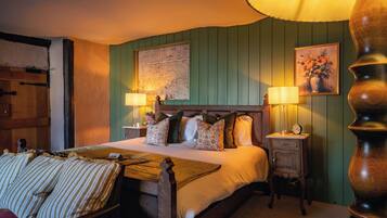 A traditional bedroom with a wooden bed, two bedside tables with lamps, a green wall, and a map.