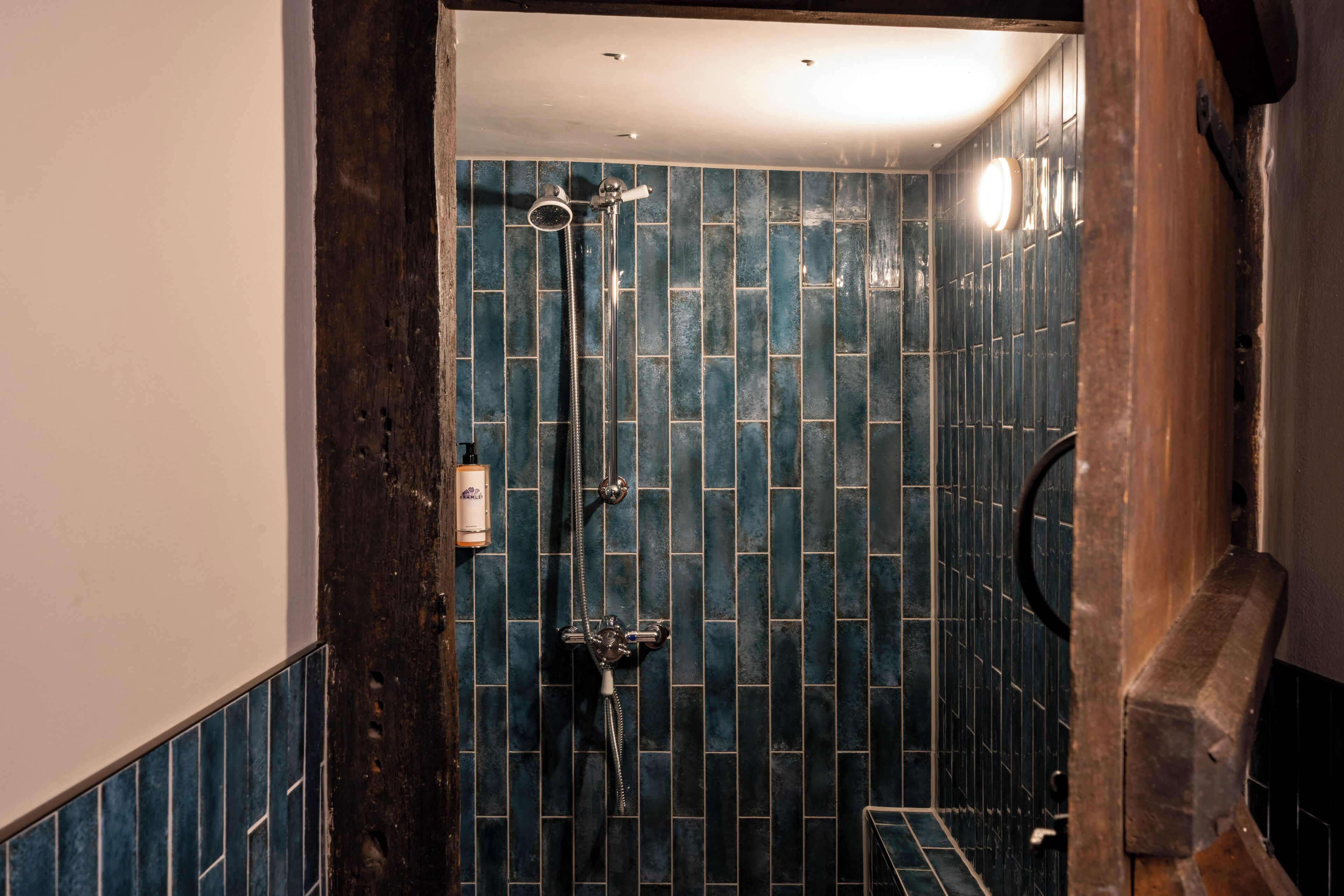 A bathroom with a shower, tiled walls, and a wooden door frame.