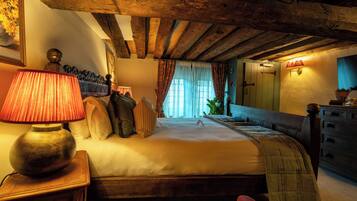 A bedroom with a wooden ceiling, a bed with pillows, a bedside table with a lamp, and a dresser.