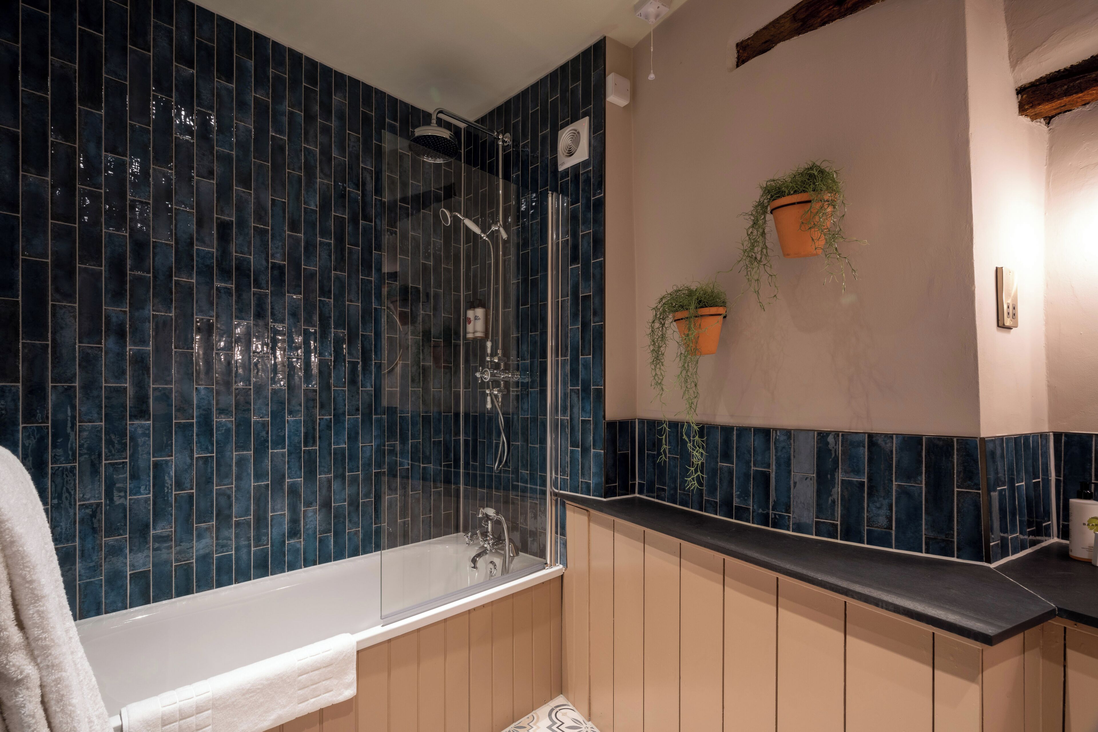 Een badkamer met een douche met glazen wand, een badkuip en houten kasten.