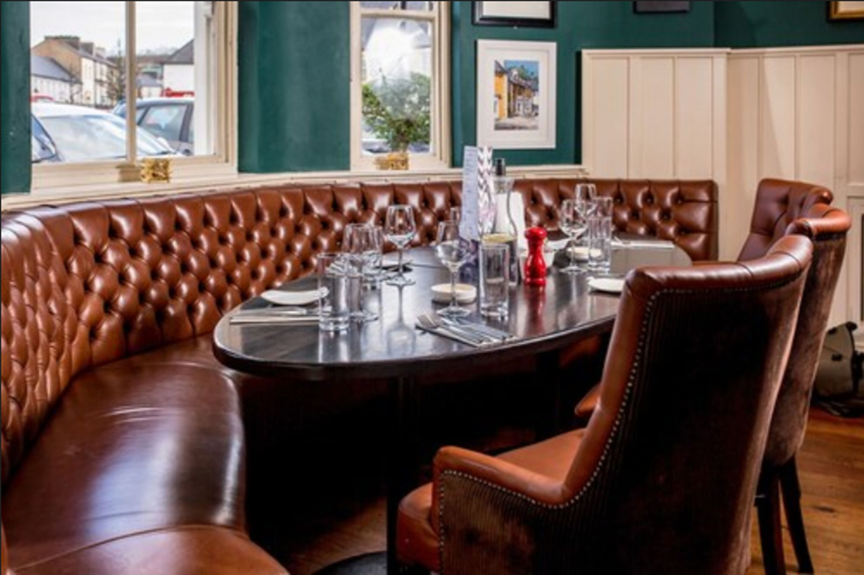 A dining area with a round table set for four, surrounded by brown leather booth seating.
