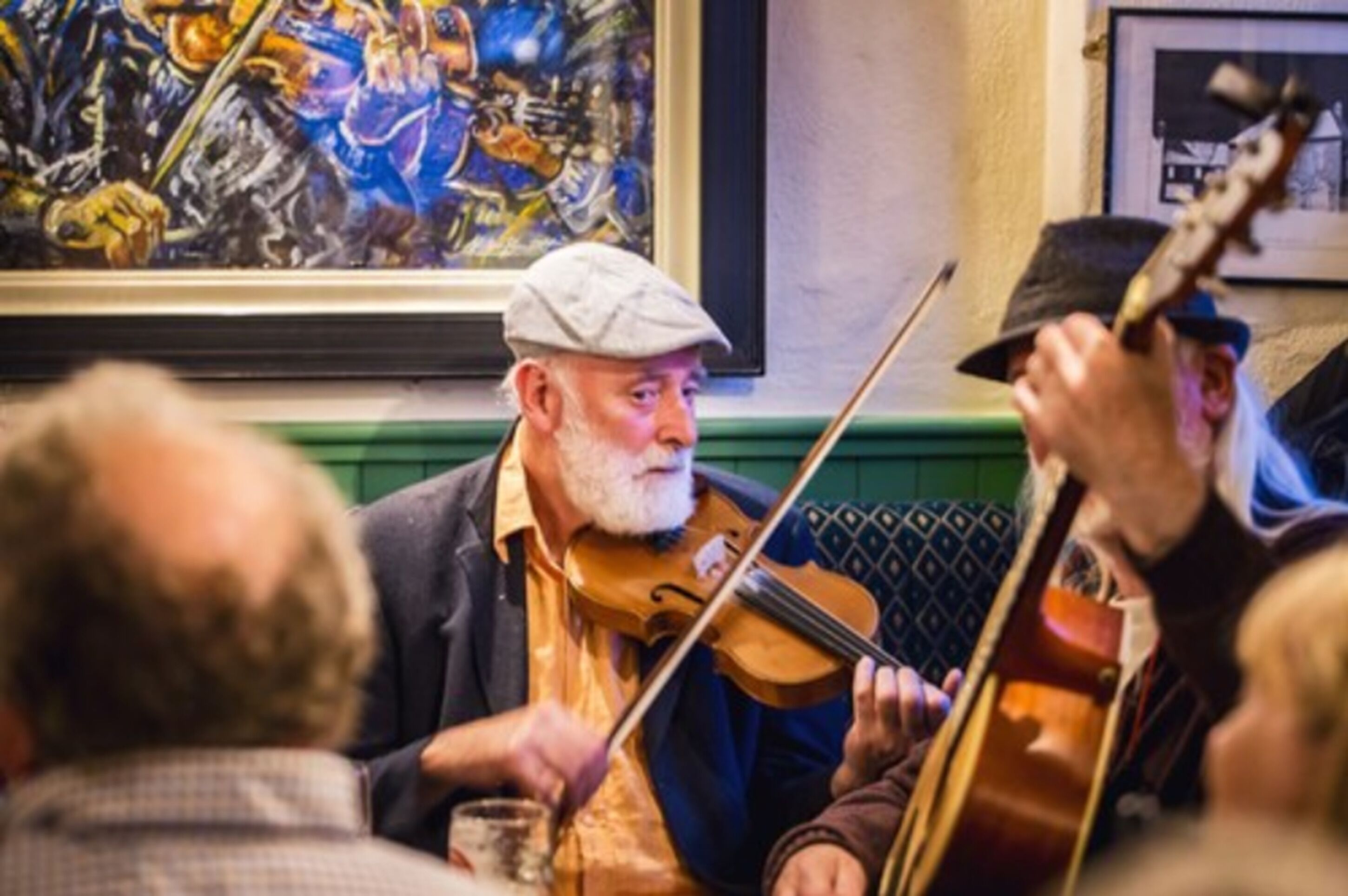 A group of people playing string instruments, likely in a social or musical gathering.