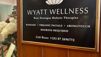 A sign for Wyatt Wellness offering services like massage, organic facials, and aromatherapy.