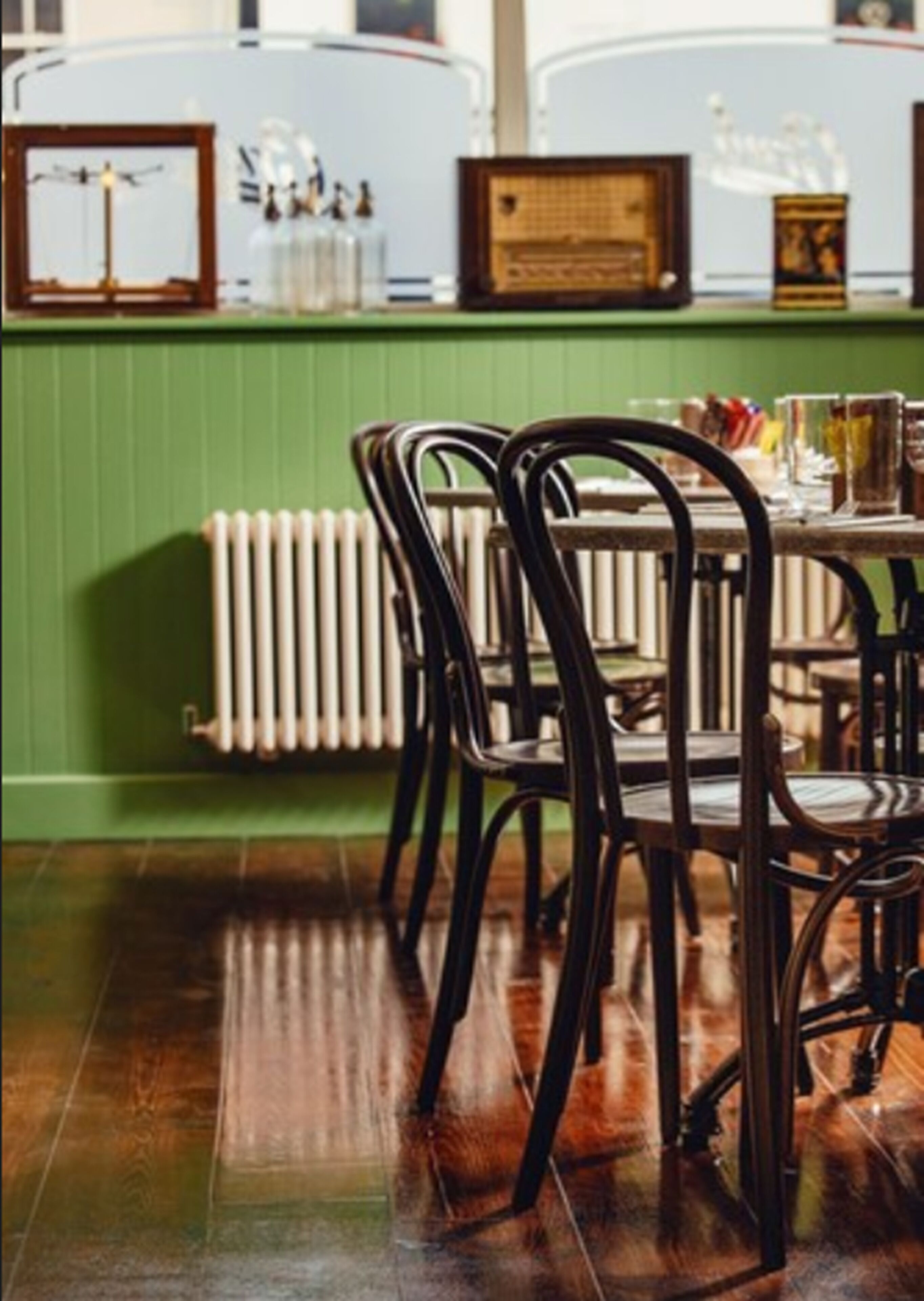 A dining area with wooden chairs and a table, a radiator, and framed pictures on the wall.