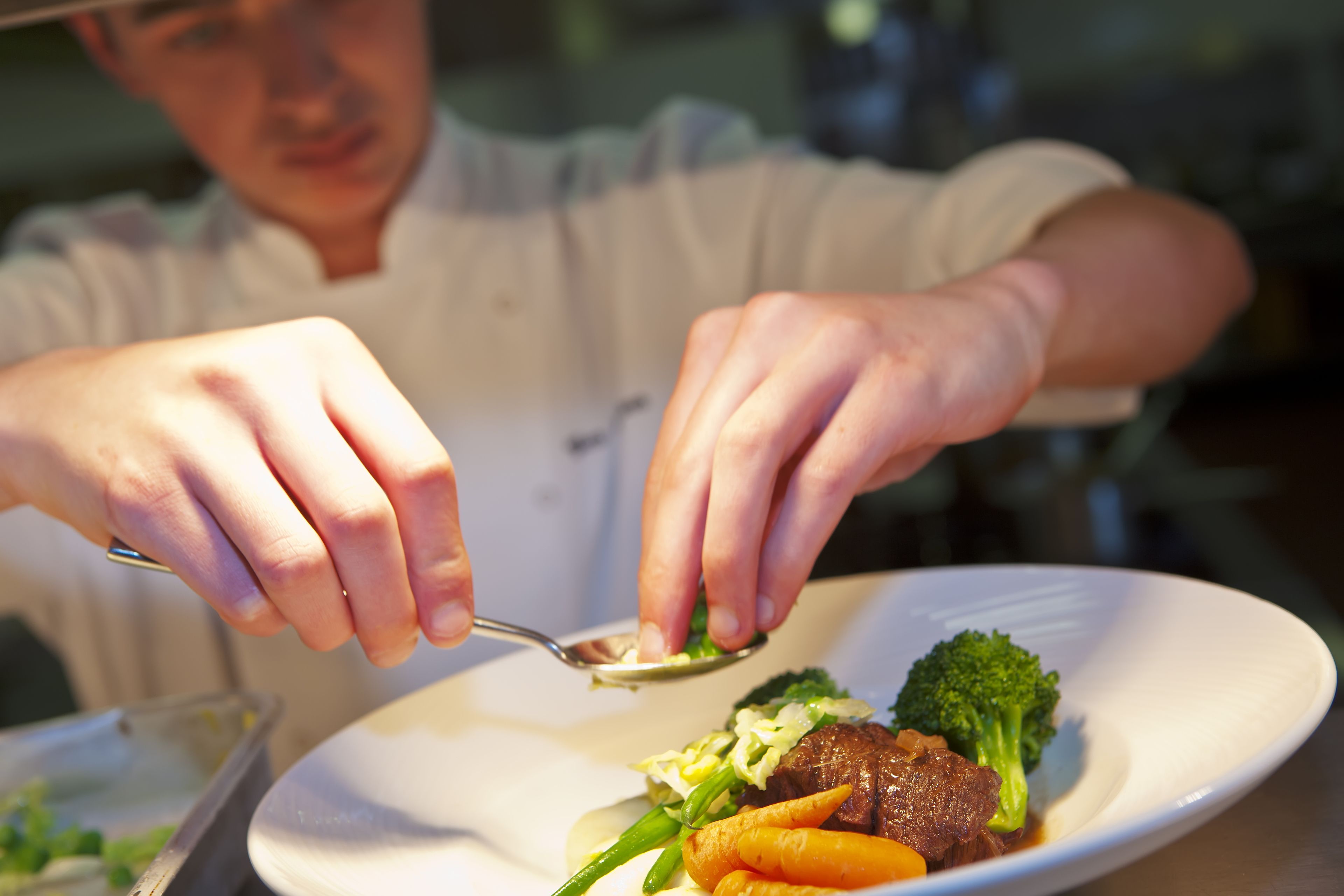 A person serving food on a white plate.