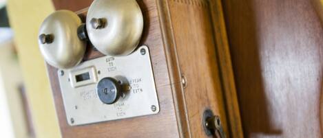 A wooden cabinet with a vintage radio and a mechanical device, possibly a typewriter, mounted on a wall.